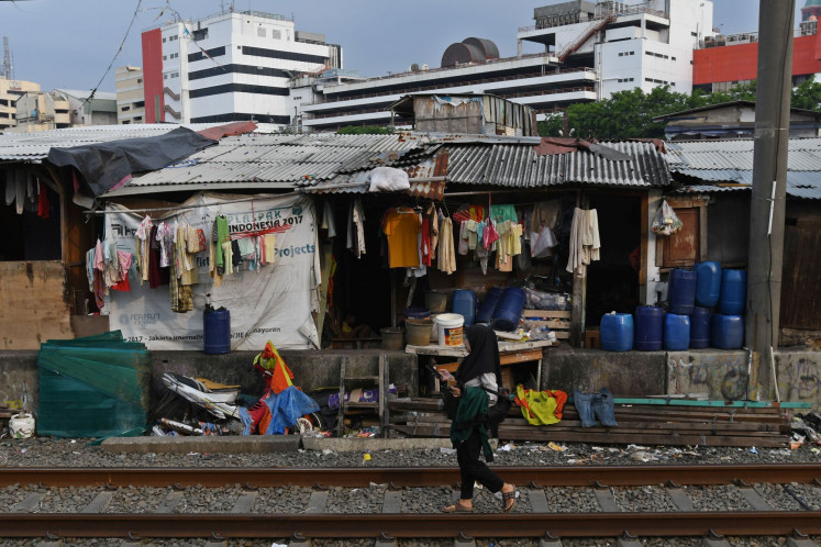 A woman walks on a railroad track running by a low-income housing area in Kampung Bandan, Central Jakarta, on Oct. 14, 2022.