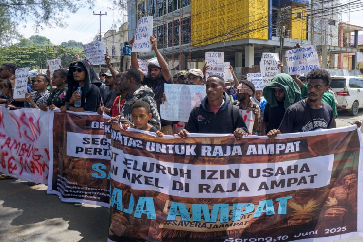Papuans hold placards reading “revoke all nickel mining permits in Raja Ampat immediately“ during a protest march to the Southwest Papua Governor's office in Sorong on June 10, 2025. 